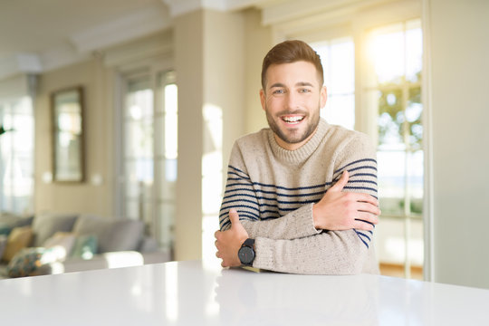 Young handsome man at home happy face smiling with crossed arms looking at the camera. Positive person.