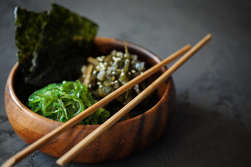 Traditional Japanese Snack - Chuka Wakame seaweed salad and crispy roasted nori sheets in wooden bowl on dark background with copy space for text.Healthy seafood high in vitamins - obrazy, fototapety, plakaty