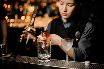 Bartender pouring an alcohol cocktail with jigger