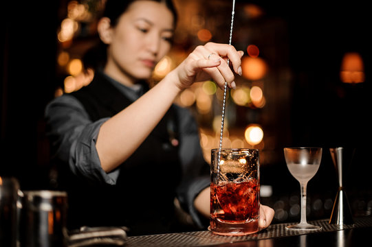 Bartender stirring alcohol cocktail with a bar spoon