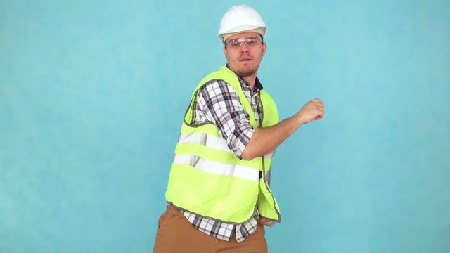 cheerful man in a construction uniform and a white helmet,dancing