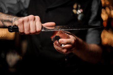 Close shot of bartender cutting ice with a knife