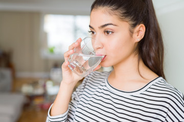 Beautiful young woman drinking a fresh glass of water at home