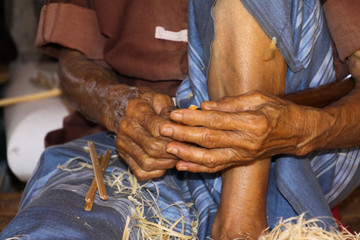 Close up of brown skinny hands of old man working with bamboo wood in a paper umbrella factory in Chiang Mai