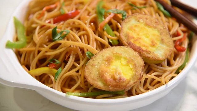 video/footage of Egg Schezwan/hakka noodles, popular indochinese food served in a bowl with chopsticks. selective focus