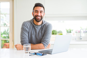 Handsome hispanic man working using computer laptop with a happy and cool smile on face. Lucky person.