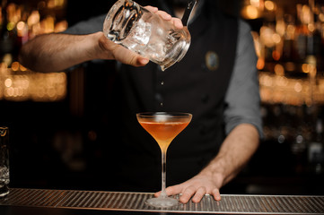 Bartender adding ice in glass from another glass