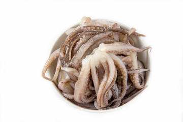 Raw squid tentacles in a bowl on white background