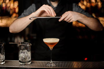 Bartender pouring an alcohol cocktail using grater