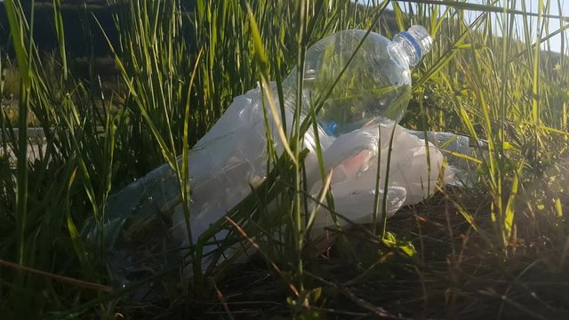 Plastic Bottles and Bag Garbage Trash Tossed By Road in Green Grass Close Up