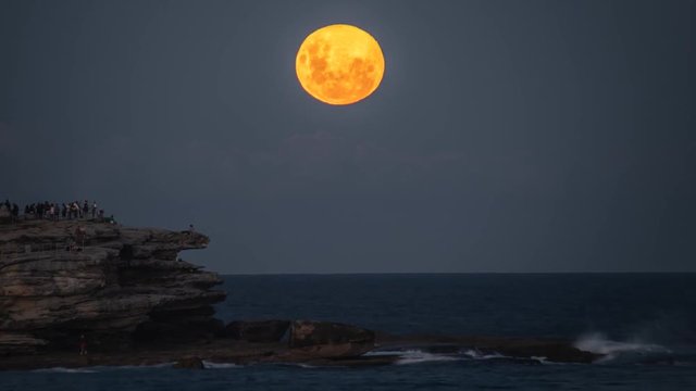 The Full Moon Rising at Bondi Beach. People viewing the moonrise from Ben Buckler.