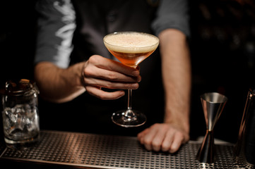 Close shot of bartender holding cocktail with foam