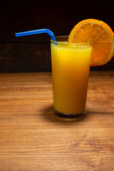 Glass of freshly squeezed orange juice on wooden table