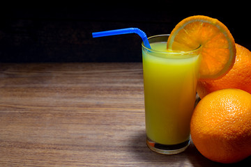 Glass of freshly squeezed orange juice on wooden table. Free space for your text.
