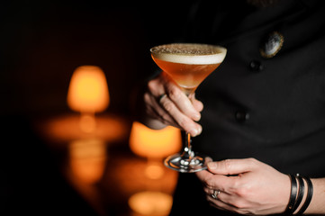 Close-up of bartender holding an alcohol cocktail with foam