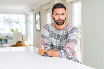 Fototapeta na wymiar Handsome hispanic man wearing casual sweater at home skeptic and nervous, disapproving expression on face with crossed arms. Negative person.