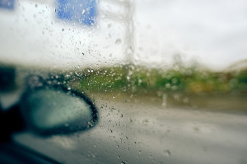 lluvia a través de la ventana del coche en movimiento por una carretera