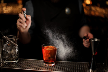 Close-up of bartender making an alcohol cocktail using sprayer