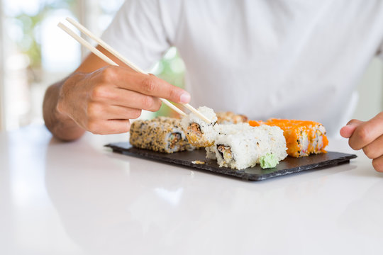 Close up of colorful sushi asian food, man hands holding sushi pieces using chopsticks