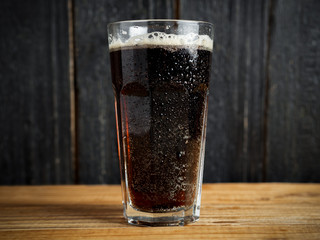 A glass of dark beer on a wooden table in the center