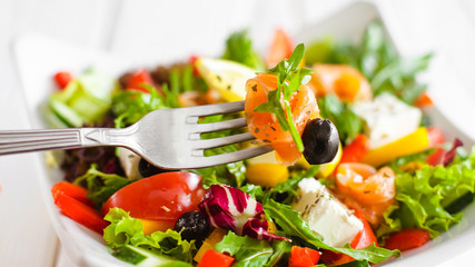 Healthy nutrition lifestyle. Closeup of rolled salmon slice on fork. Blurred vegetable salad background.