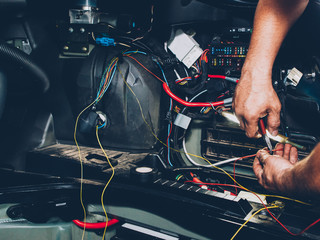 Mechanic electrician checking repairing upgrading wiring. Auto service workshop. Regular preventive...