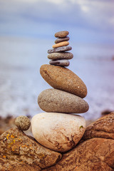 Fototapeta na wymiar Balance, relaxation and wellness: Stone cairn outside, ocean in the blurry background