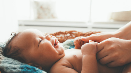 Newborn baby smiling at mother. Happy motherhood. Mom holding cute little child hands with love and...