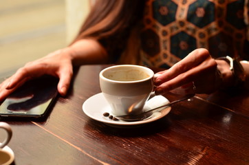 The girl drinks coffee in the cafe.