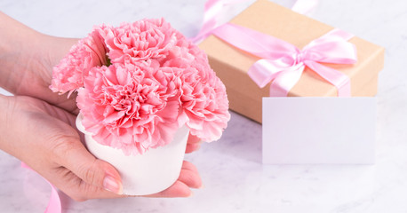 Design concept - Woman giving carnations bouquet on marble white background, top view, copy space, close up, mock up. Mothers day idea inspiration.
