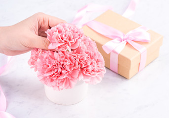 Design concept - Woman giving carnations bouquet on marble white background, top view, copy space, close up, mock up. Mothers day idea inspiration.