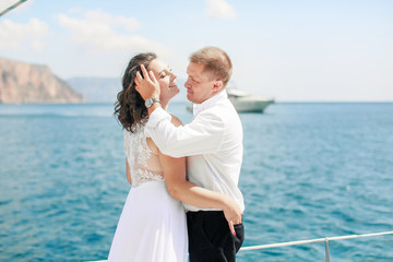 Fototapeta na wymiar A Just married couple on yacht. Happy bride and groom on their wedding day