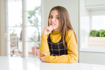 Young beautiful blonde kid girl wearing casual yellow sweater at home Thinking worried about a question, concerned and nervous with hand on chin
