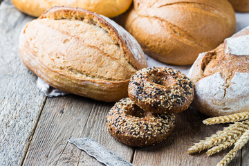 Assortment of fresh baked bread and buns on wooden table background