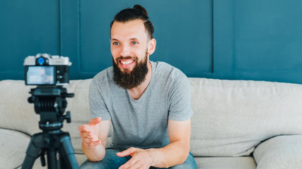 Social media influencer creating content. Smiling bearded hipster guy shooting video using camera...