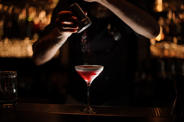 Bartender sprinkles the alcohol cocktail in glass