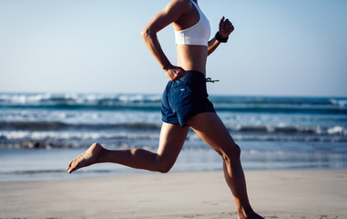 young fitness woman running at sunrise beach