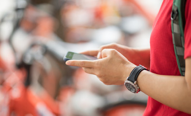 Hands using smartphone scanning the QR code of shared bike in city