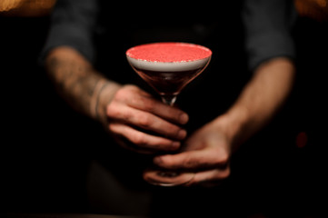 Close-up of tattooed bartender holding an alcohol cocktail