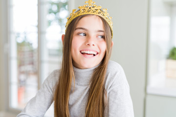Beautiful young girl wearing a golden crown as a princess from fairytale looking away to side with smile on face, natural expression. Laughing confident. © Krakenimages.com