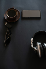 cup of coffee, sun glasses, smartphone, headphones on a black background