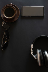 cup of coffee, sun glasses, smartphone, headphones on a black background