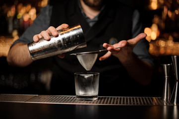 Close-up of bartender holding shaker and sieve