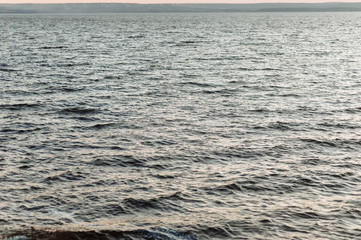Raging river and sea as background. Small waves at sunset.