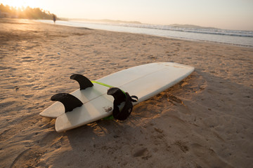 Surfboard on sandy beach in the sunrise