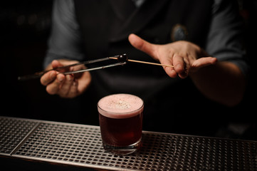 Bartender putting cherry on toothpick with forceps
