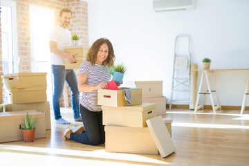 Fototapeta na wymiar Middle age senior couple moving to a new house, smiling woman holding cardboard boxes and packaging