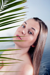 Porträt einer zarten Frau, die aus Palmblatt schaut