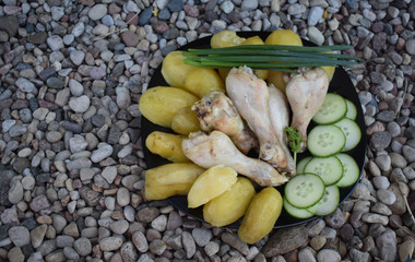 The food on the black dish on the stones.