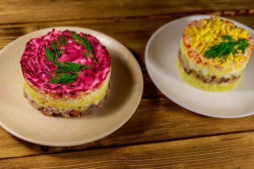 Traditional russian layered salads "Mimosa" and "Herring under a fur coat" (shuba) on wooden table